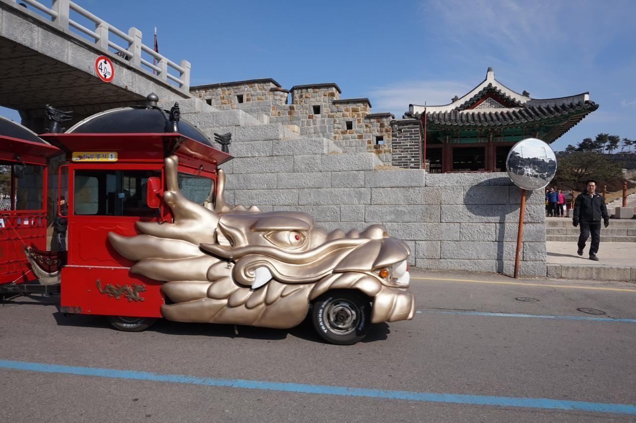 水原華城的小火車，前面裝飾有金色龍頭，顯示出火車的獨特設計和在街道上的行駛狀況。