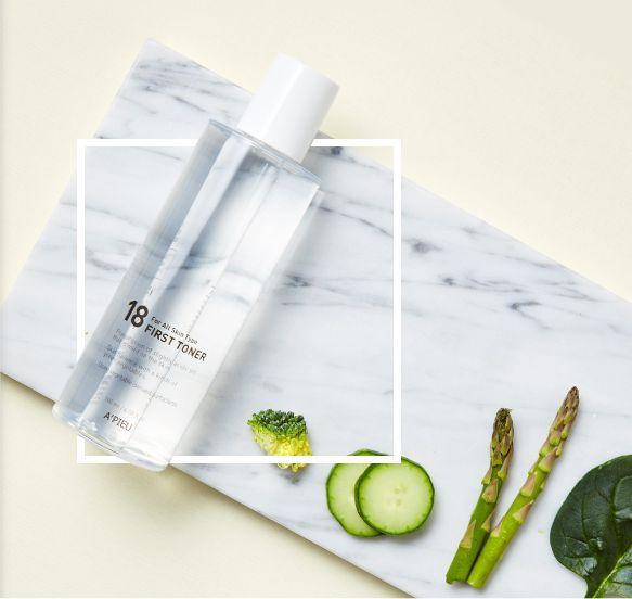 A'PIEU 18 First Toner placed on a clean setting with vegetables, emphasizing its natural ingredients and soothing effects.