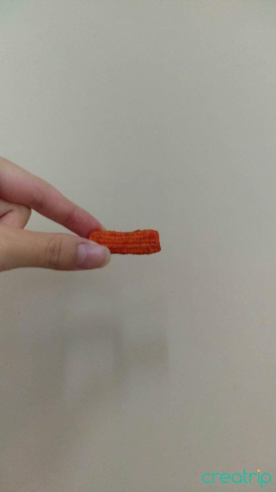 韓國辣炒年糕餅乾單片展示，呈現其條狀扭曲的形狀，適合路上小吃愛好者。