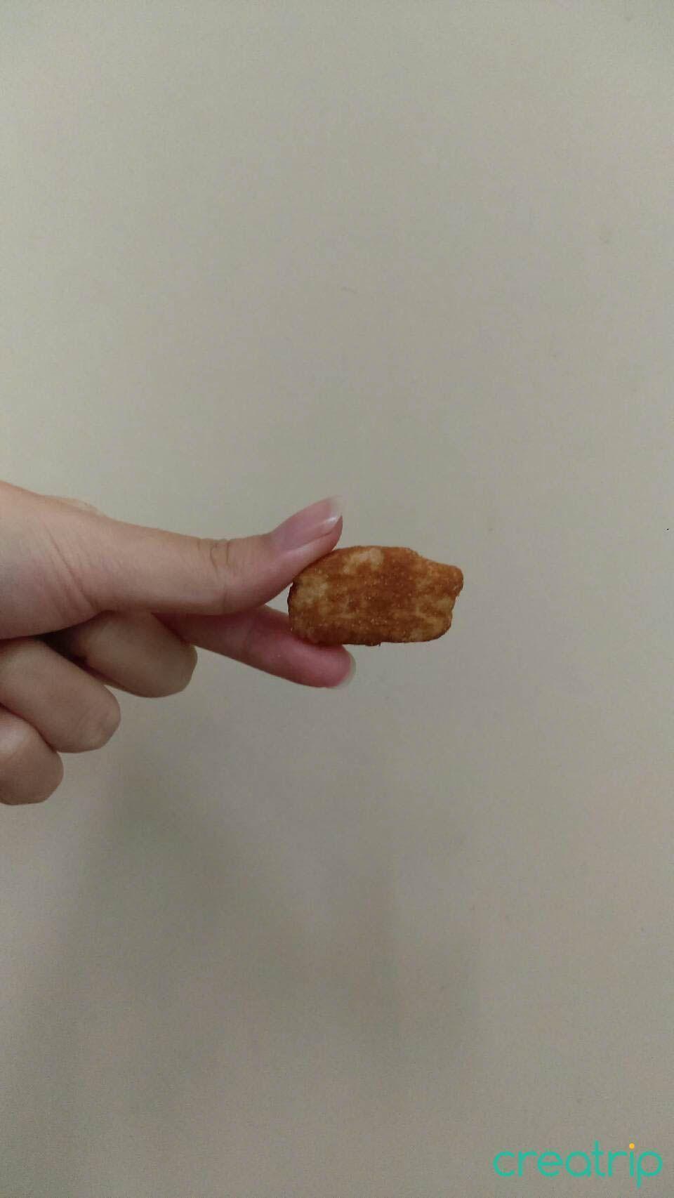 手持單個韓國豆粉米餅乾，展現其扁平且刮A片狀的外觀，適合喜愛豆味的人。