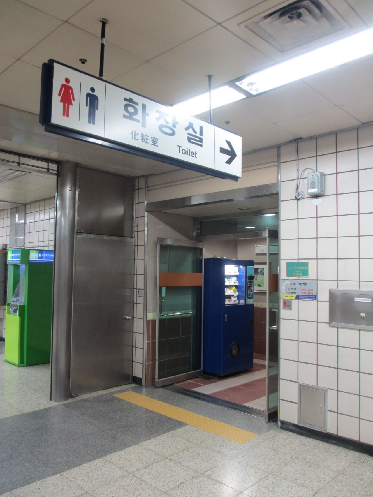 韓國地鐵站內的廁所標識，飛利浦自動販賣機旁邊有洗手間入口。