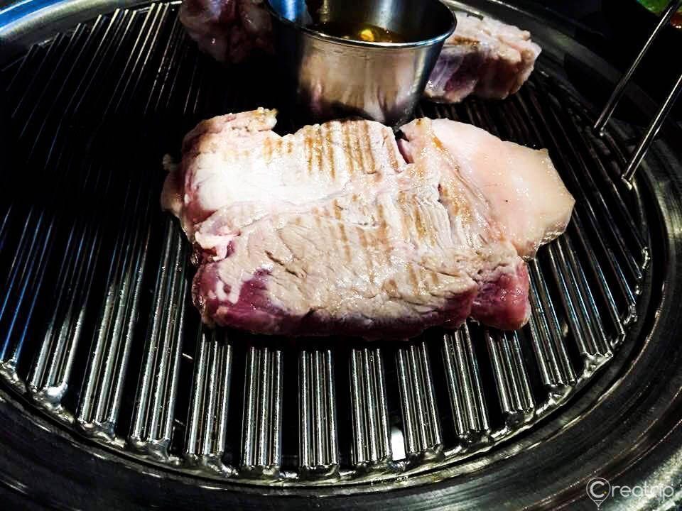 在烤架上炭火烤製的大塊濟州豬肉，濃鬱的香氣和美味，401餐廳必吃。