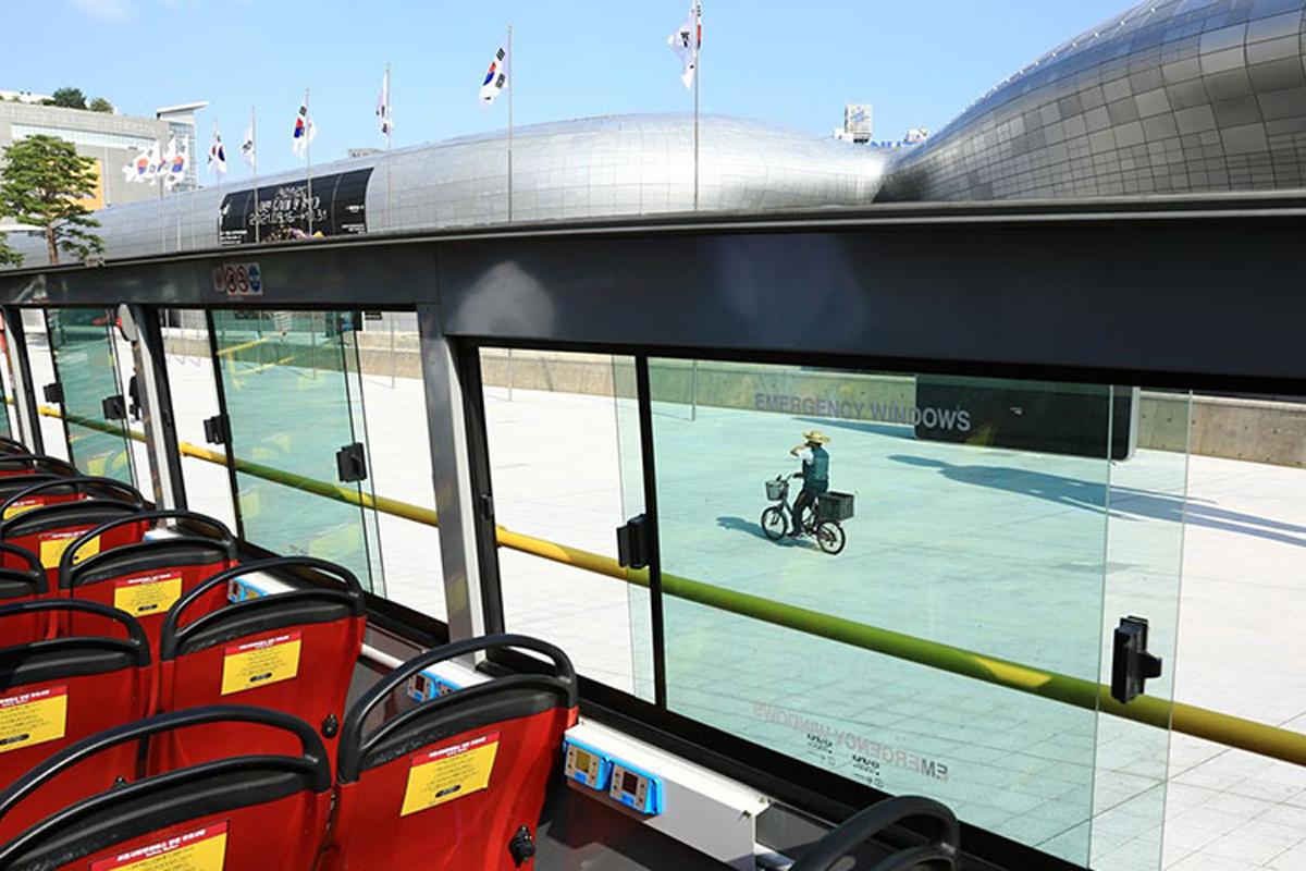Interior of the Seoul City Tour Bus showing comfortable red seating with a modern exterior view