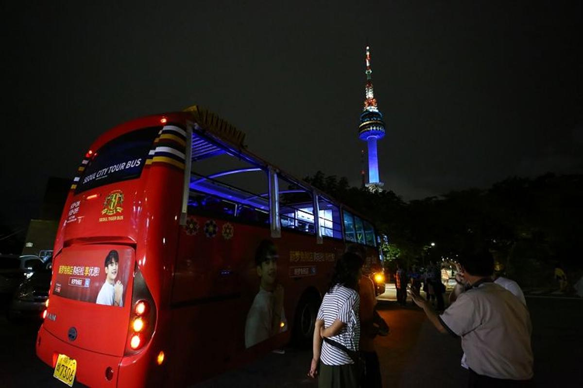 Seoul City Tour Bus stopped for a night view at Namsan Tower with tourists exploring the area