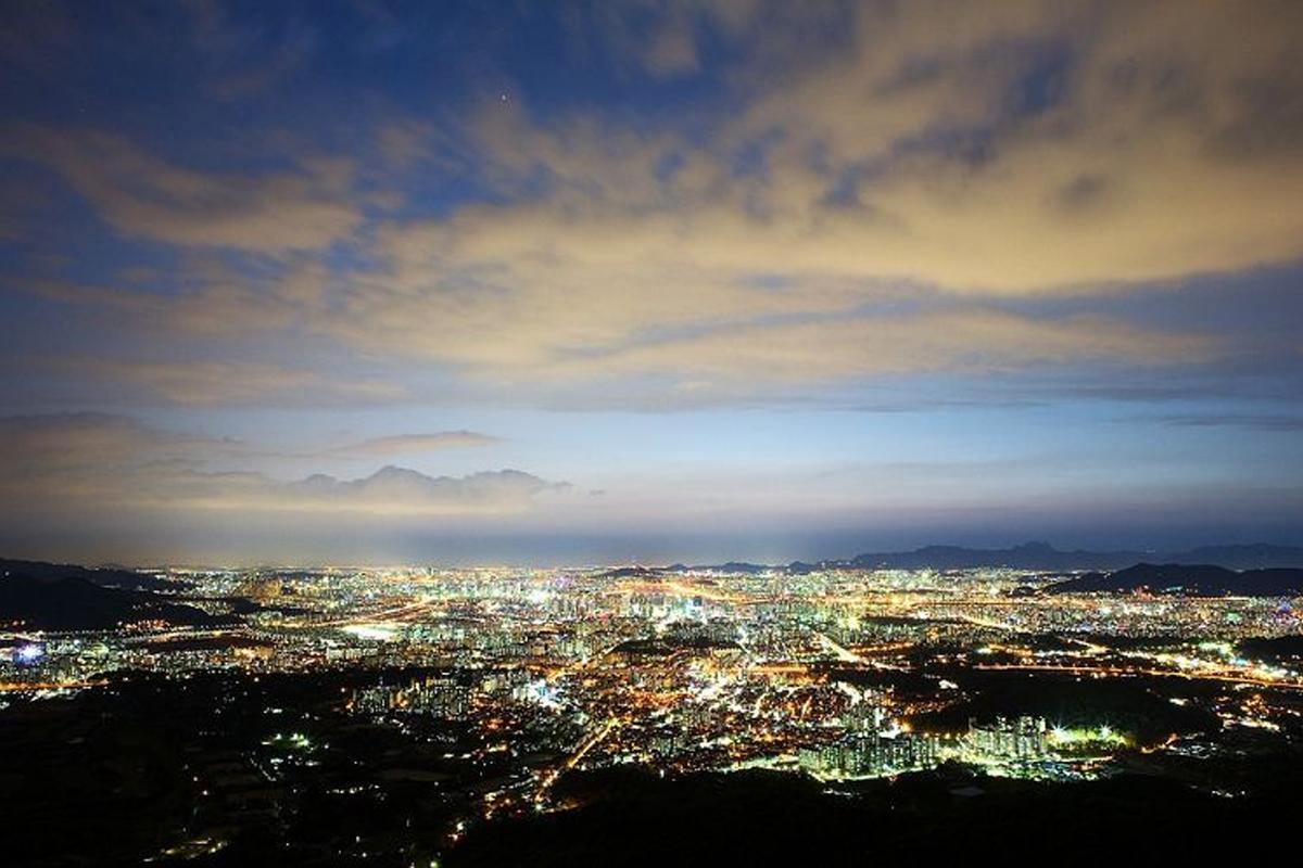 A panoramic night view of Seoul city lights from Namsan Mountain, highlighting the vibrant urban landscape