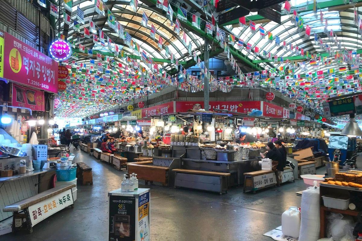 廣藏市場的熱鬧氛圍,顯示人羣擁擠和多樣攤位,展示市場受歡迎的景象。