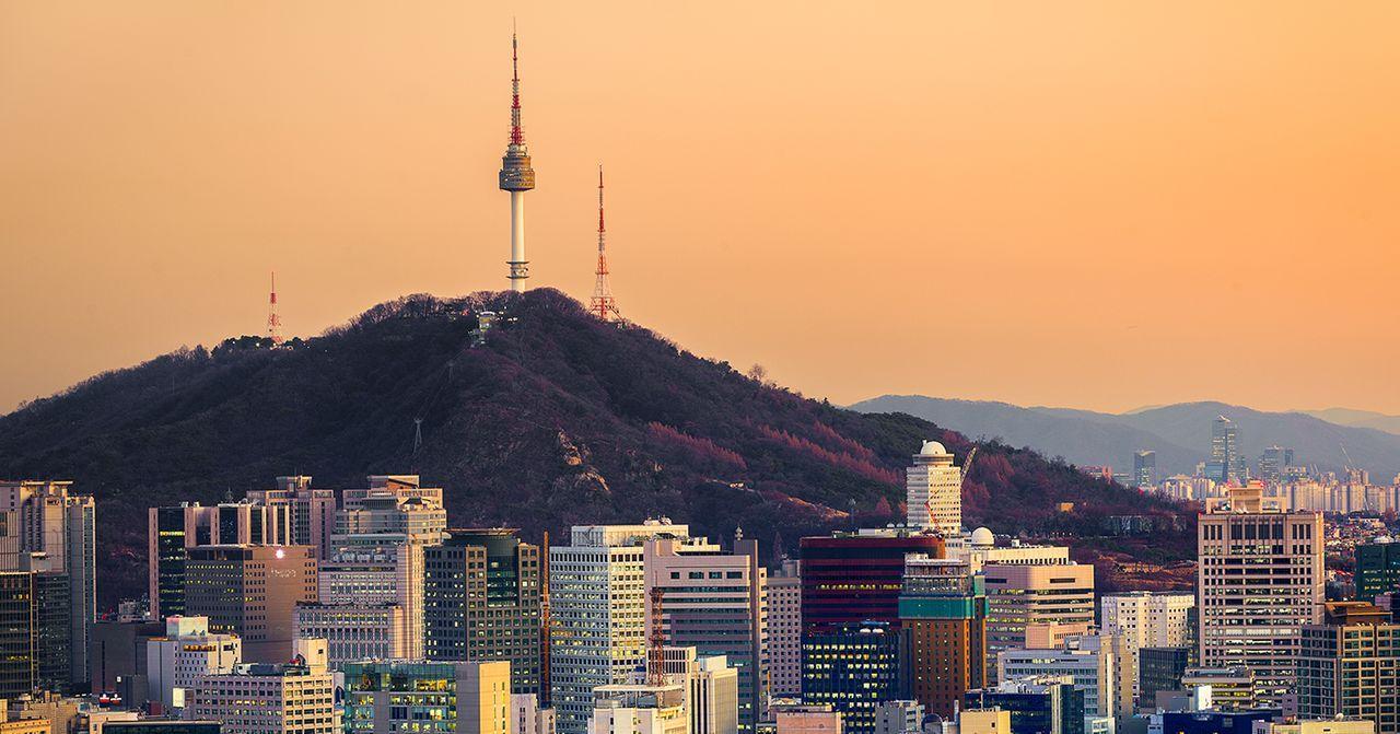 首尔黄昏全景，南山塔矗立于中心，城市风光与自然景色融合。