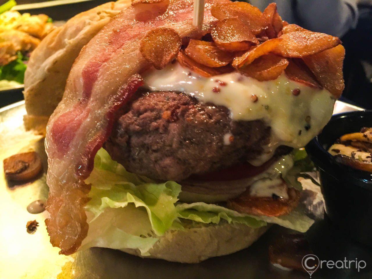 Nahaufnahme eines saftigen Burgers mit Speck und Salat, serviert in Itaewon, Seoul.