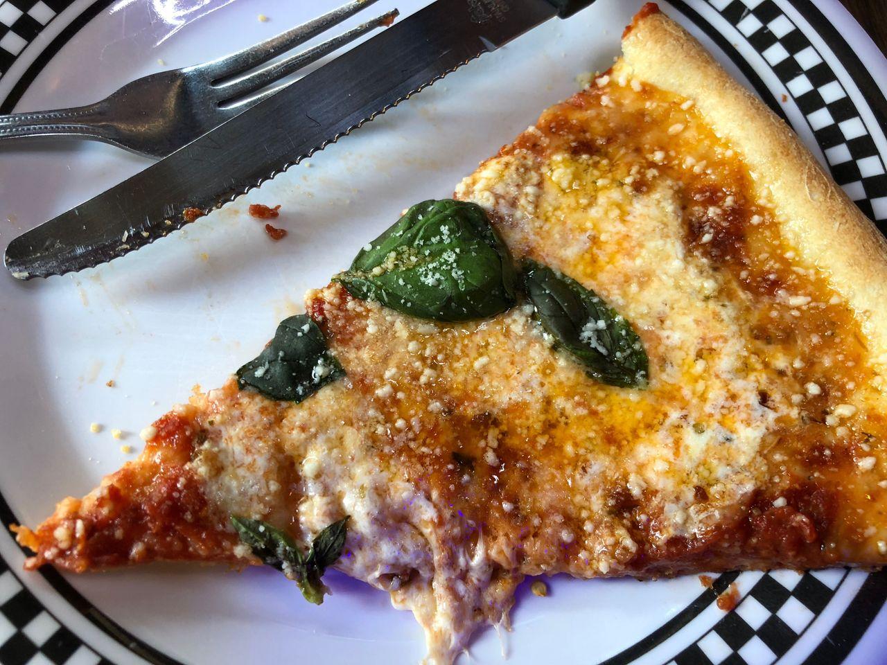 Nahaufnahme eines Pizzastücks mit frischen Basilikumblättern in einem italienischen Restaurant in Itaewon, Seoul.