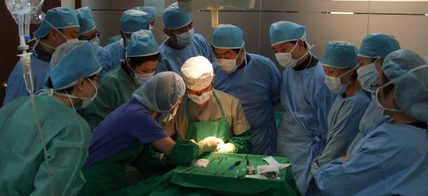 Group of surgeons performing a cosmetic surgery procedure, highlighting the expert teamwork and advanced medical practices in Korean plastic surgery.