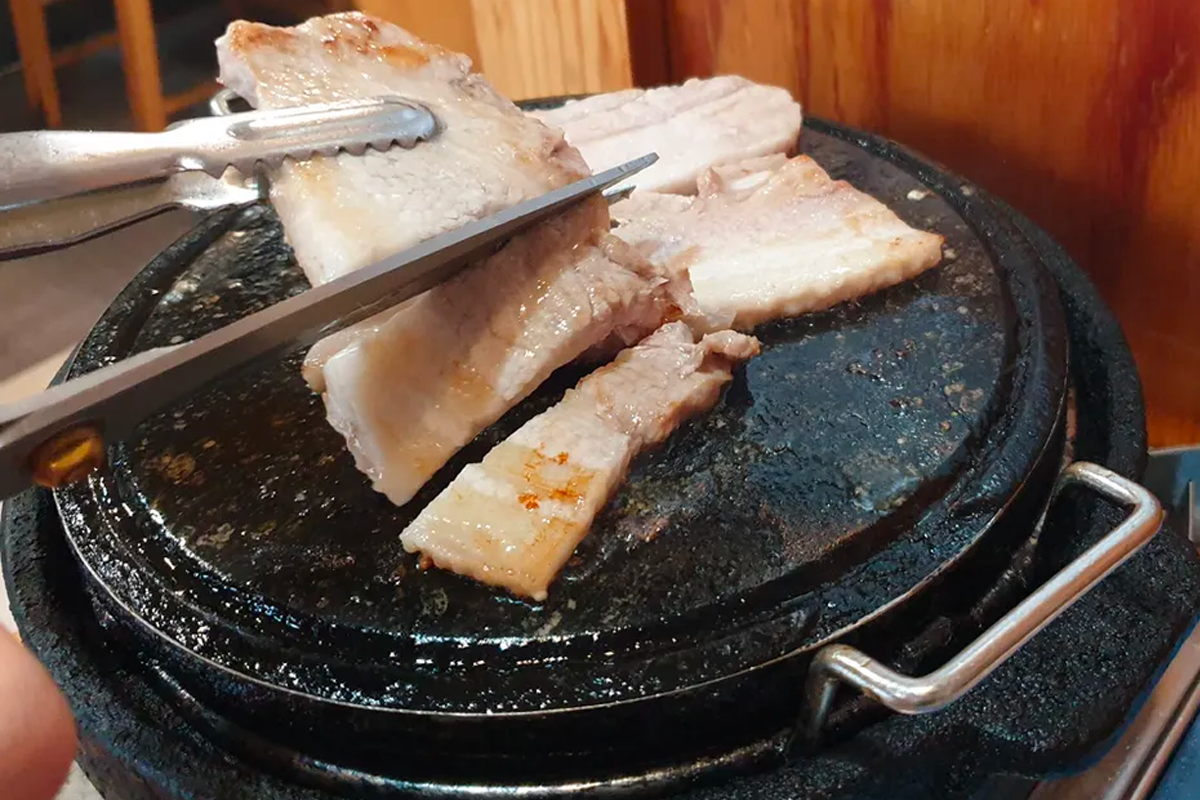 Close-up of Korean barbecue meat being prepared on a grill, showcasing the delicious option for solo diners at Korean restaurants.