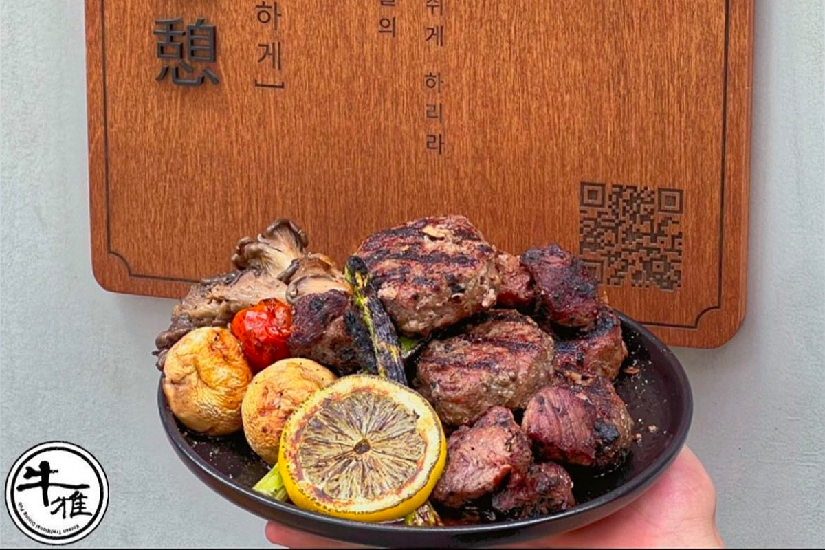 A plate of grilled meat served with lemon and mushrooms at a Korean restaurant, highlighting solo dining experiences.