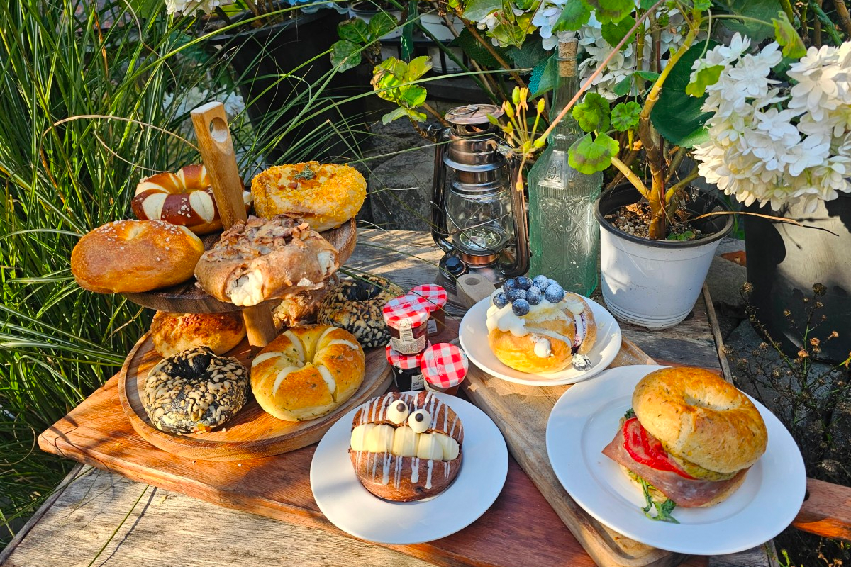 A selection of bagels and pastries presented on a tiered stand among vibrant greenery, ideal for solo dining at Korean cafes.
