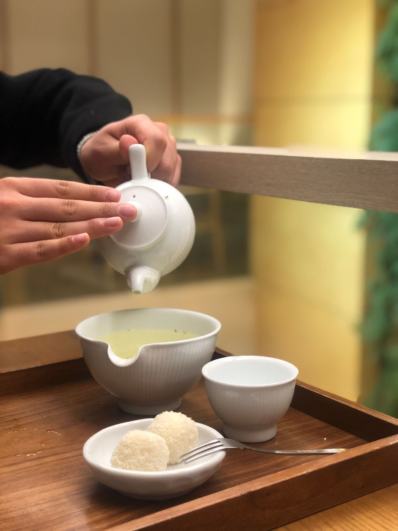 Pouring tea from a white teapot into a cup at O