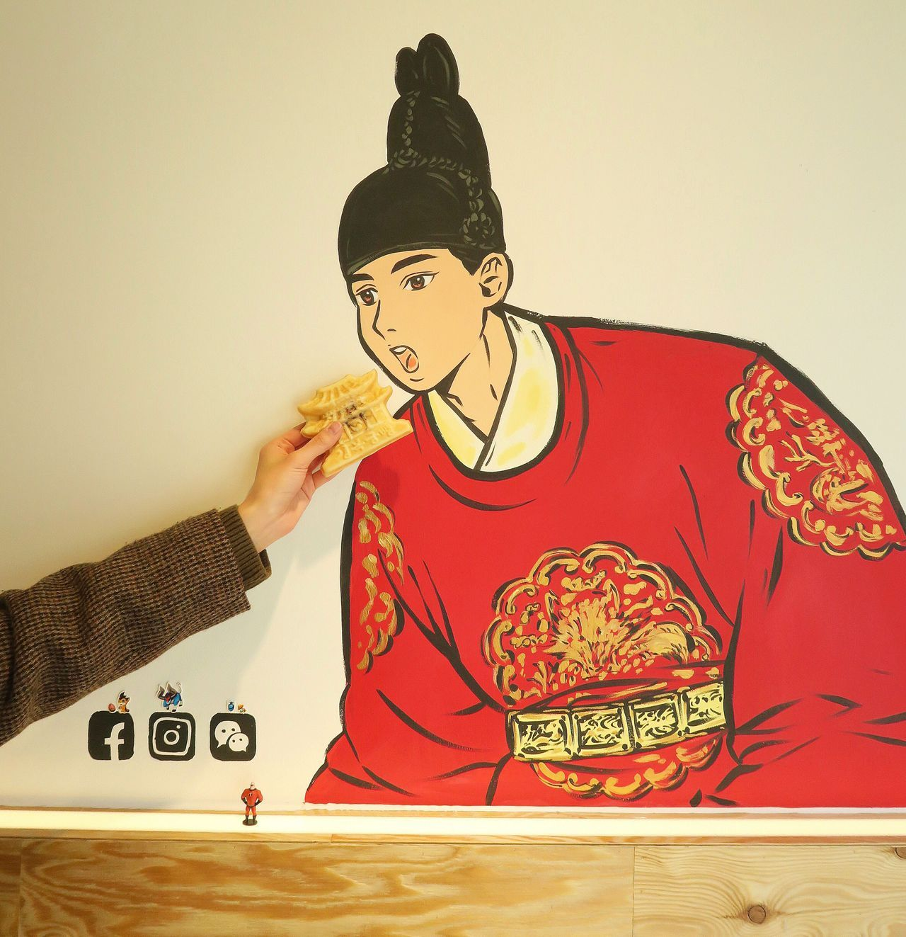 Pastry being offered to a mural painting of a traditional Korean person at Gyeongbokgung Bbang