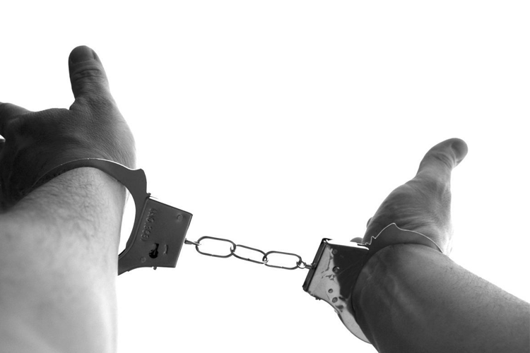 Image of hands in handcuffs, representing consequences and issues related to collective behavior and accountability in society.
