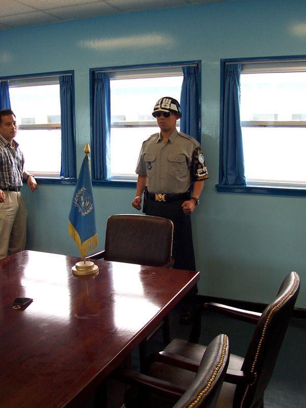 韓國板門店內的聯合國會議室，展示了一名身穿軍裝的警衛，背景是會議桌，代表了南北韓和平對話的場所。