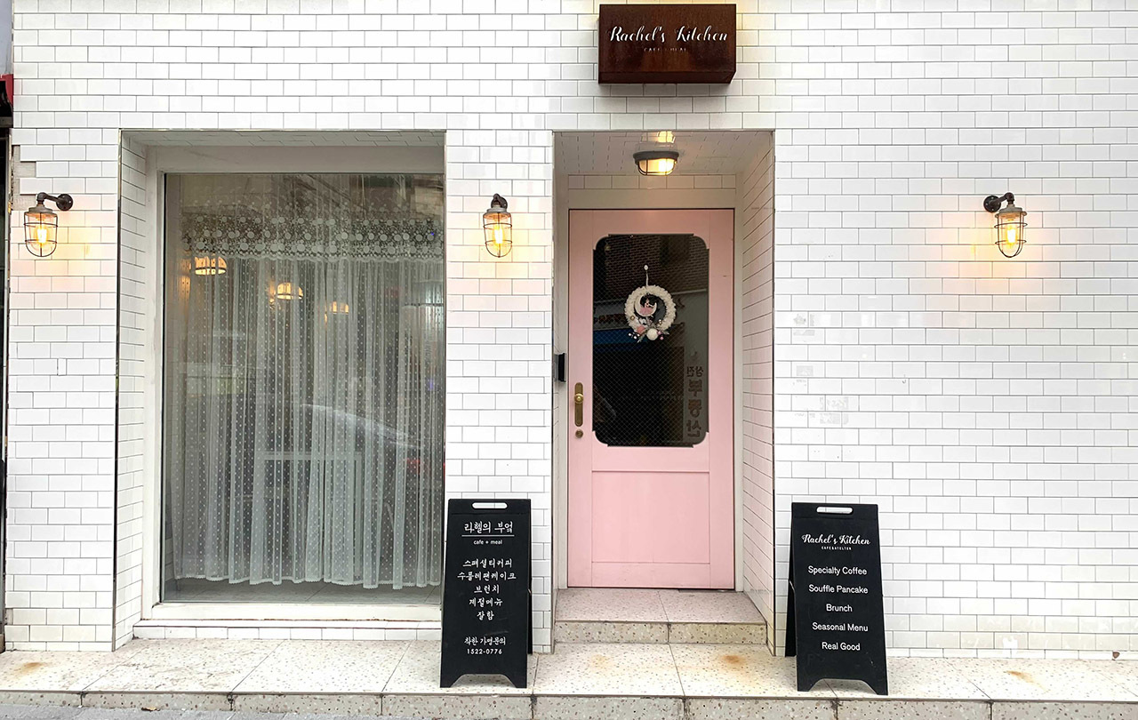 Charming entrance of Rachel's Kitchen in Hongdae, inviting visitors with a pastel-themed facade.
