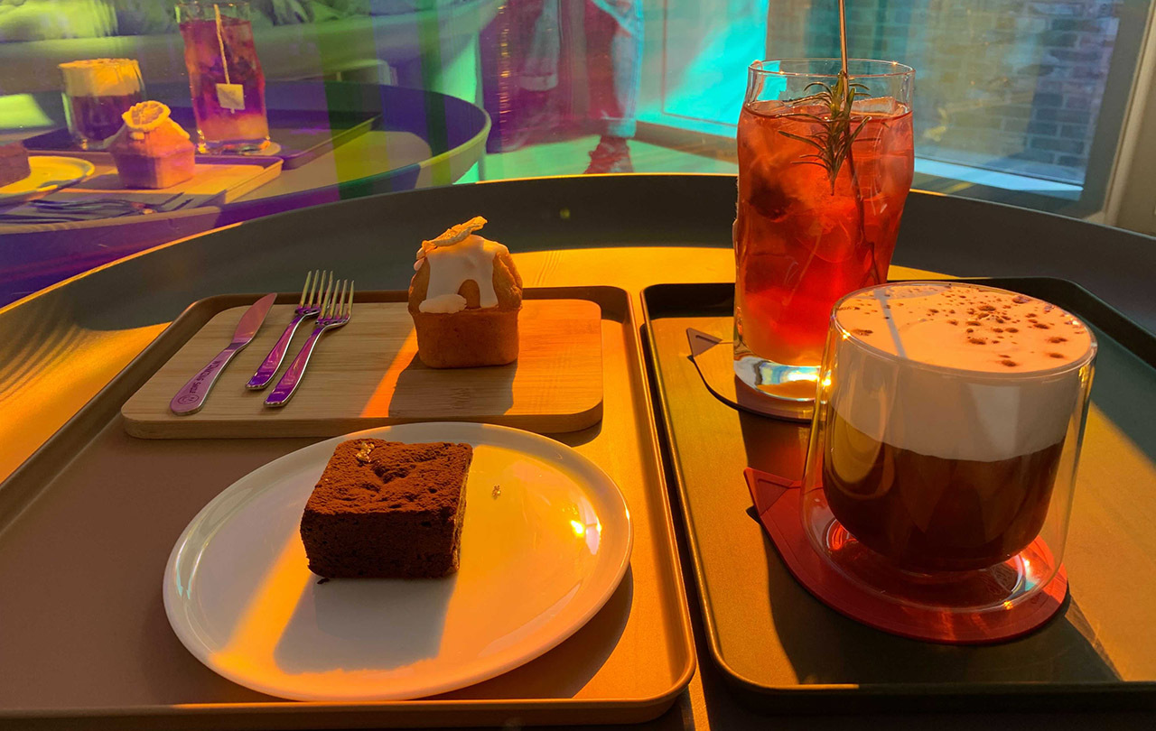 Trendsetting drinks and desserts at Cafe Aurora, showcasing a stylish presentation under colorful ambient lighting.