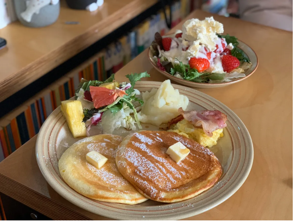 Delicious breakfast set at Butter Milk featuring fluffy Ricotta pancakes, bacon, eggs, and fresh salad.