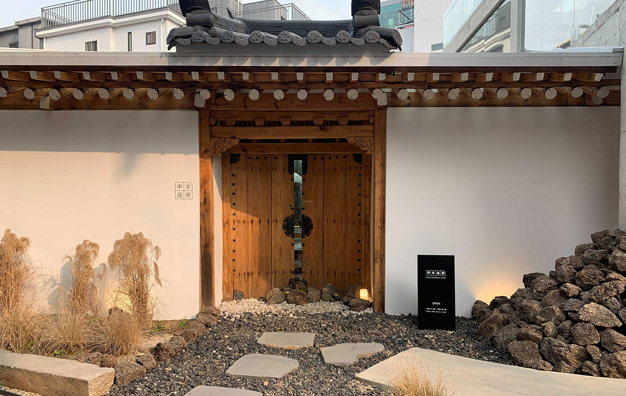 Entrance of Shinidoga, a traditional Korean Hanok cafe in Hongdae, showcasing its wooden gate and serene exterior.