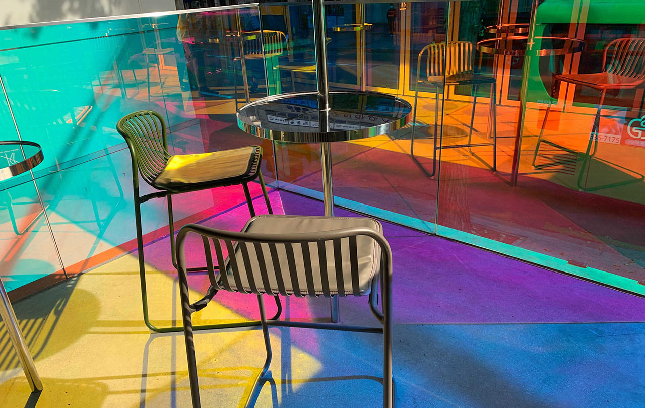 Cafe Aurora's vivid outdoor seating area with colorful, transparent glass creating a kaleidoscope effect.