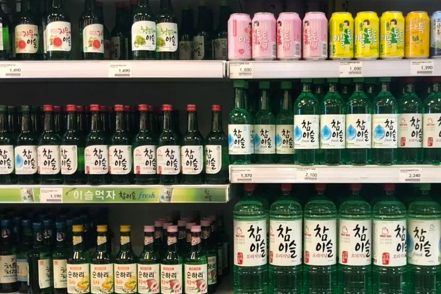 超市货架上排列整齐的韩国烧酒和饮料瓶子，展示年龄计算在酒类购买货物管理中的应用和社会政策影响。