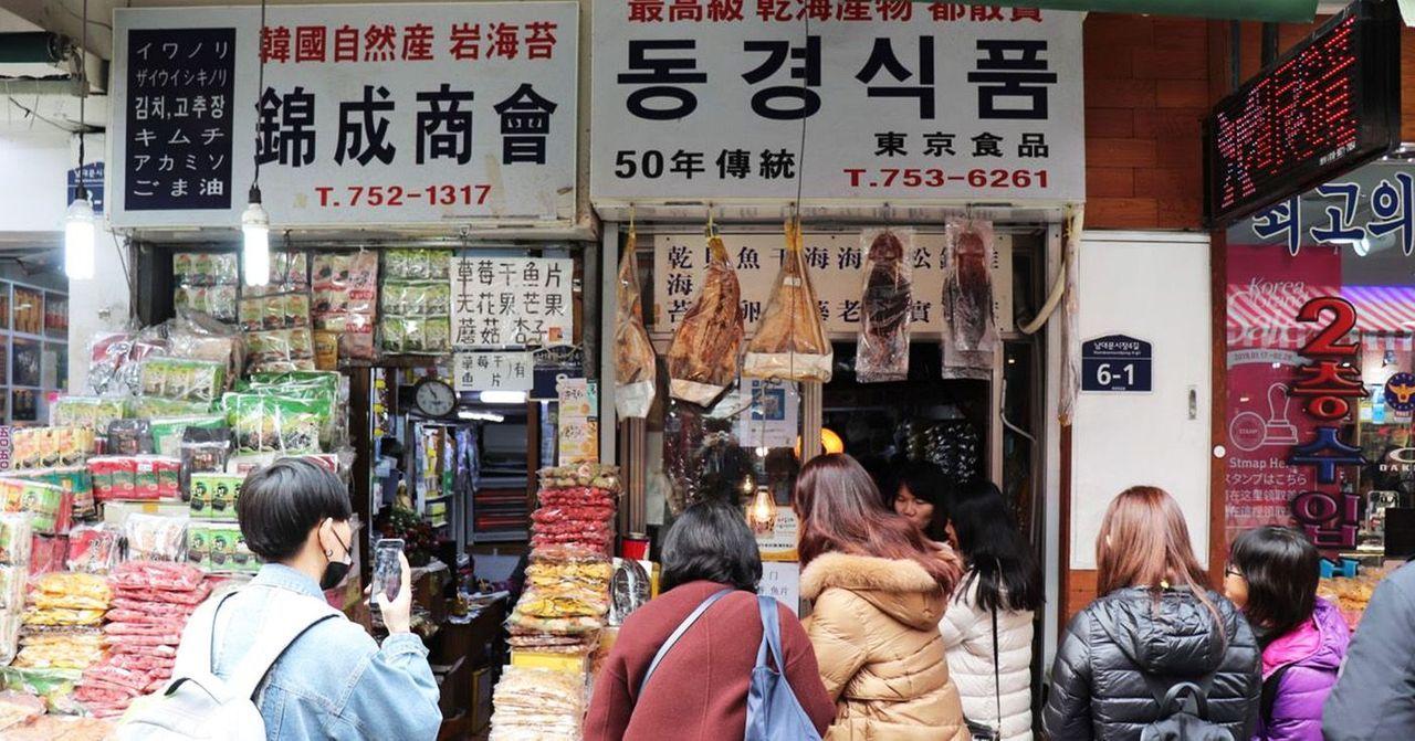 Diverse selection of goods and bustling activity at a food market stall in Namdaemun Market, Korea.