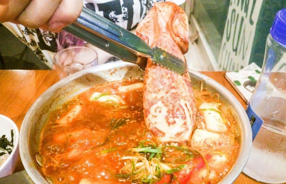 韩国 '做饭的男人' 店内出锅的辣炒年糕，配有整只鱿鱼，为辣炒年糕增加了一层豪华感。연남동의 매운 떡볶이 가게 '밥 해주는 남자'에서 맛볼 수 있는 물고기와 떡볶이.