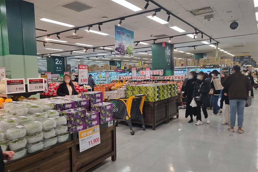 emart內部的新鮮蔬果區域，顧客正在選購水果