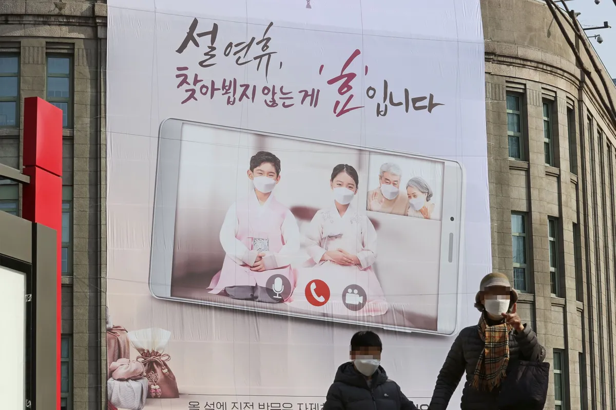 A large advertisement poster featuring a traditional Korean family scene displayed on a building.