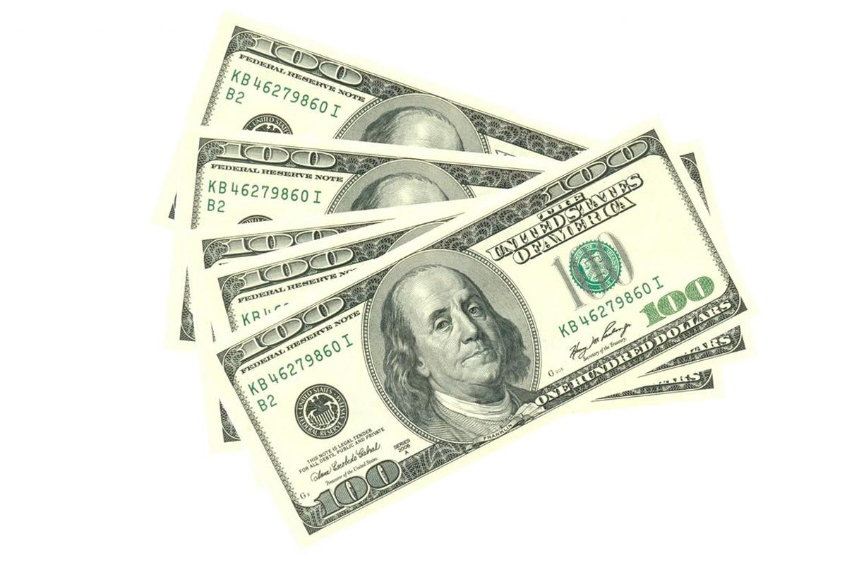 數張100美元鈔票排放整齊，淺白背景，部分鈔票重疊。