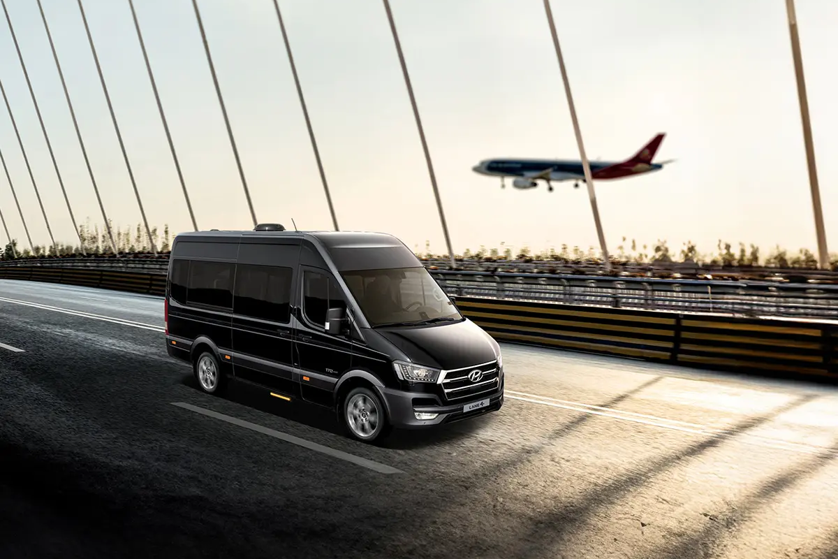 正在機場橋上行駛的私人包車，背景有飛機飛過，藍天色調的景色。