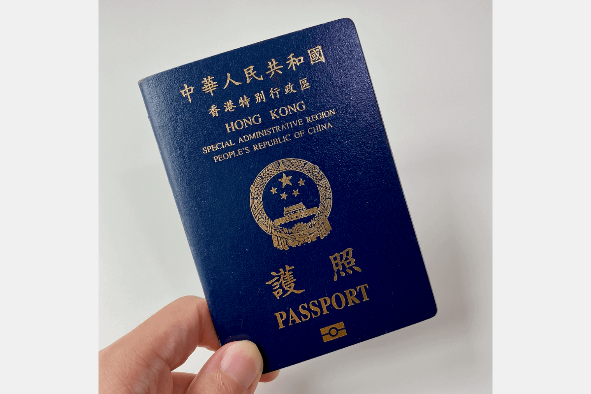 藍色香港特區護照的封面，持有人正用手指持著護照。