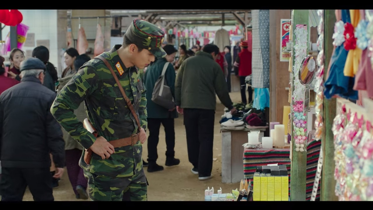 A Korean military officer and a woman inside a house, representing domestic life in North Korea from 'Crash Landing on You'