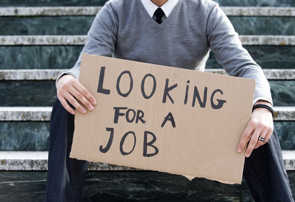 Unemployed individual holding 'Looking For a Job' sign illustrating defector's challenges in South Korea