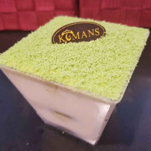韩国甜品店 KOMANS 的抹茶提拉米苏,顶部撒有抹茶粉,摆放在桌面上