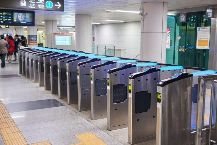 韩国地铁站检票口，背景有乘客经过。