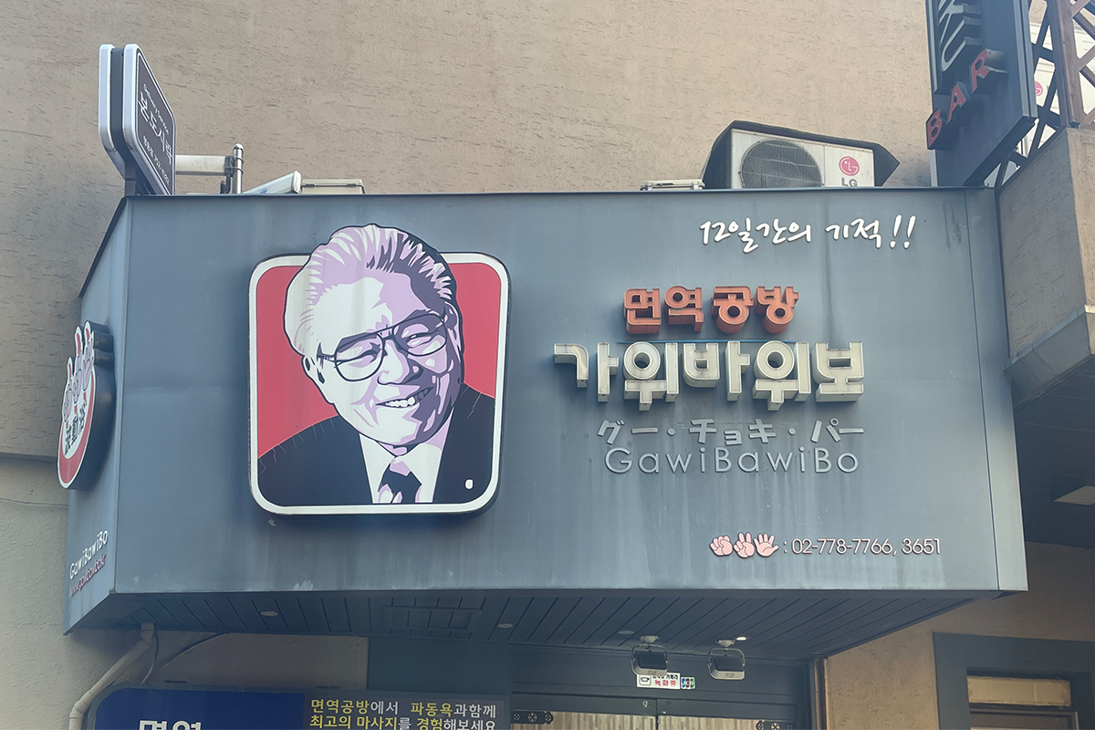 明洞免疫工房的招牌，上有韓語名稱及“GawiBawiBo”文字，配有可愛卡通插圖。