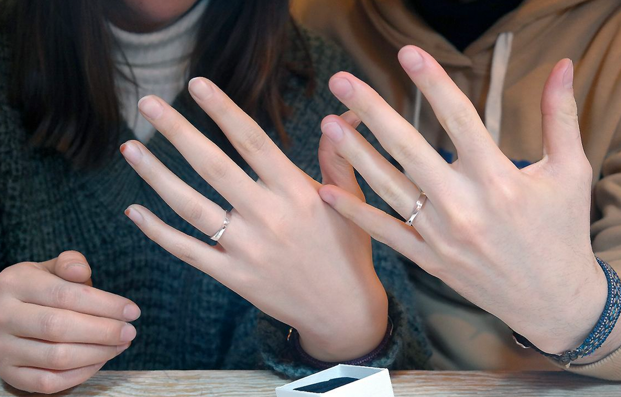一对情侣展示他们亲手制作的银戒指，手部特写镜头