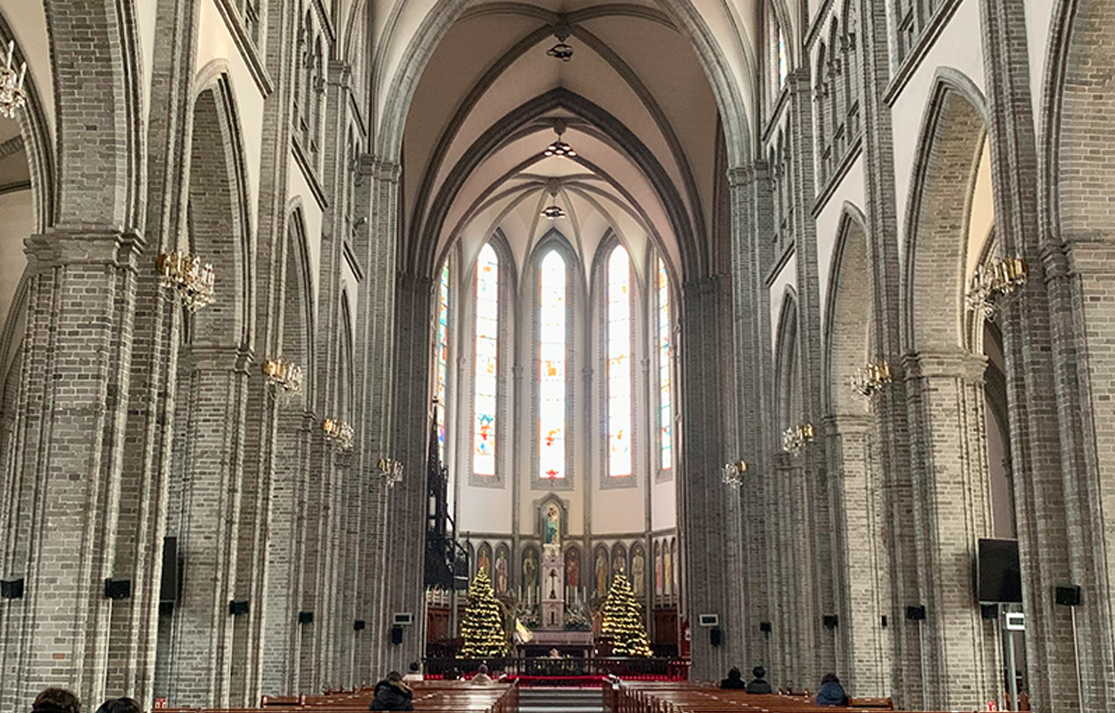 明洞大教堂内部，灰白色石墙和彩色玻璃窗，宁静庄严的氛围