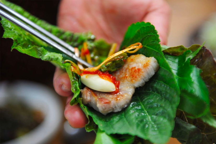 Dipping a juicy slice of 삼겹살 into sesame oil with salt, a popular Korean BBQ sauce combination