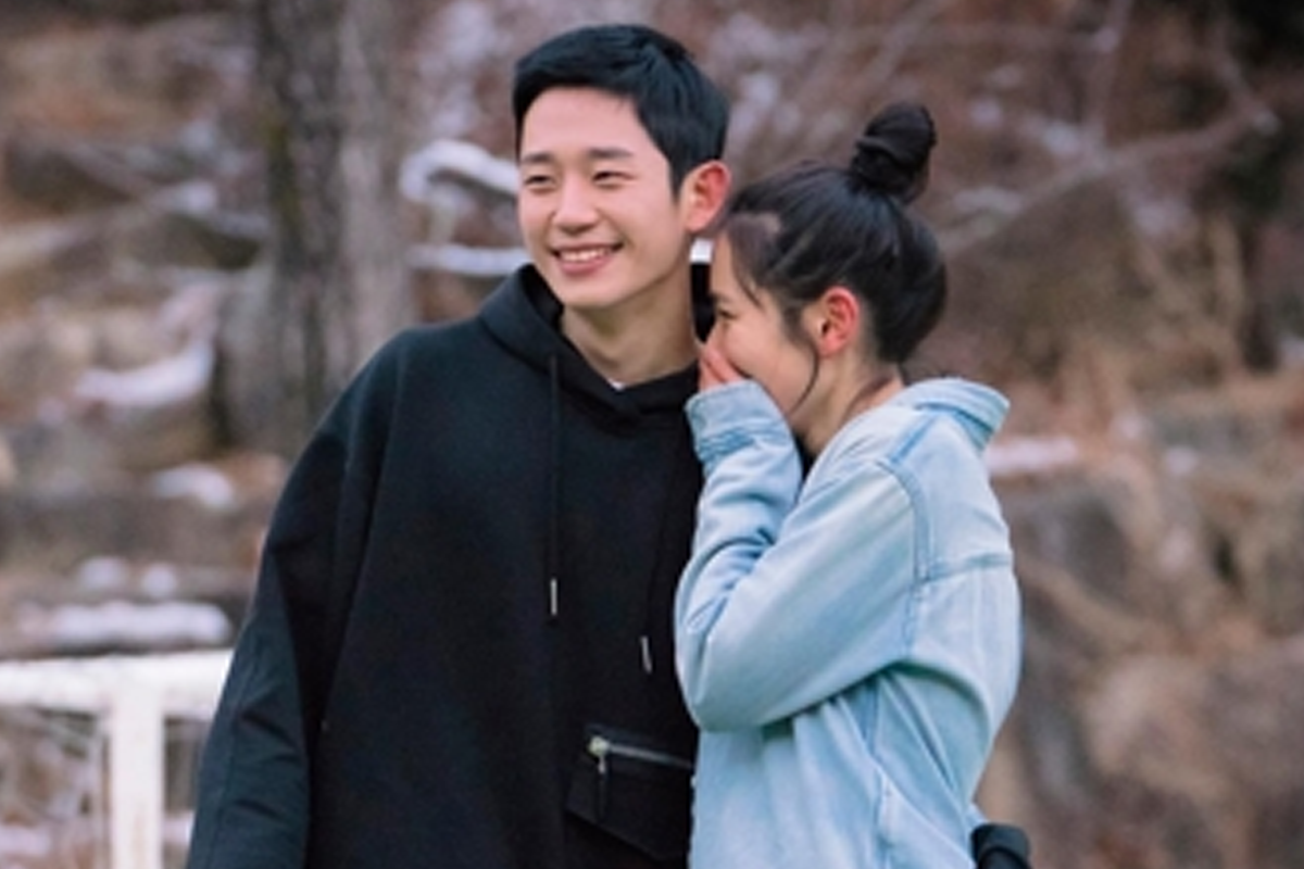 一對在户外野行中相互依偎的年輕人，描述韓國情侶間的親密互動