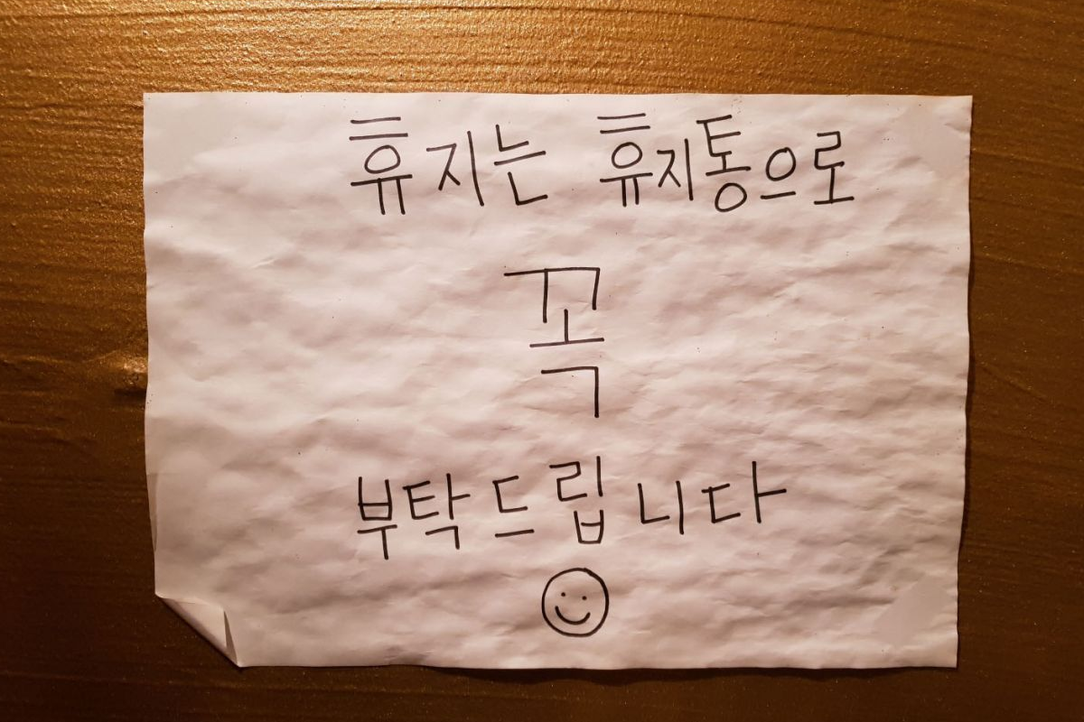 提示牌上寫著請利用垃圾桶處理廁所紙巾以避免堵塞，示範韓國公共設施使用指南