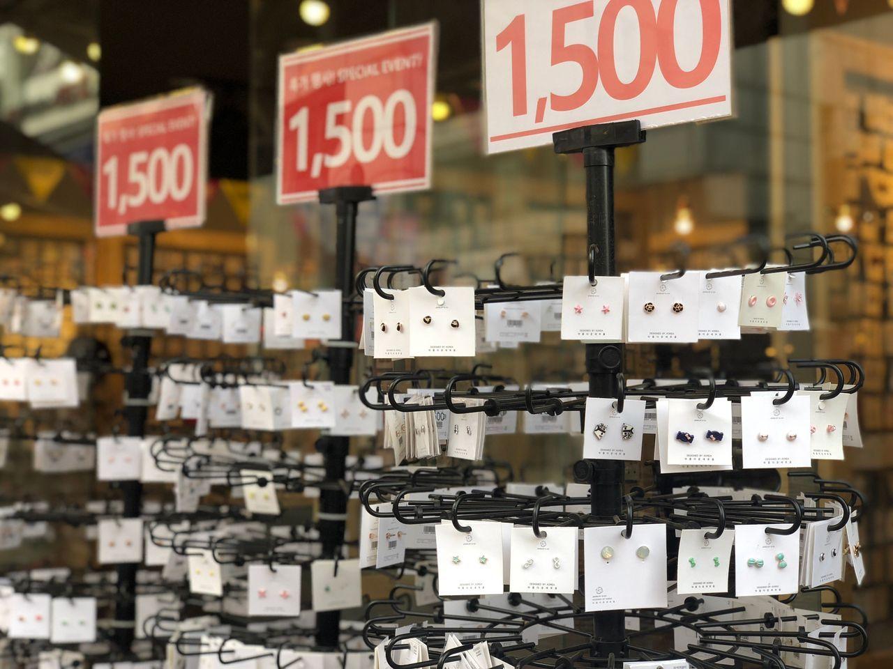 SALE 50店外に展示された様々なピアスとイヤリング。表示価格と特別セールのサインが目立ちます。