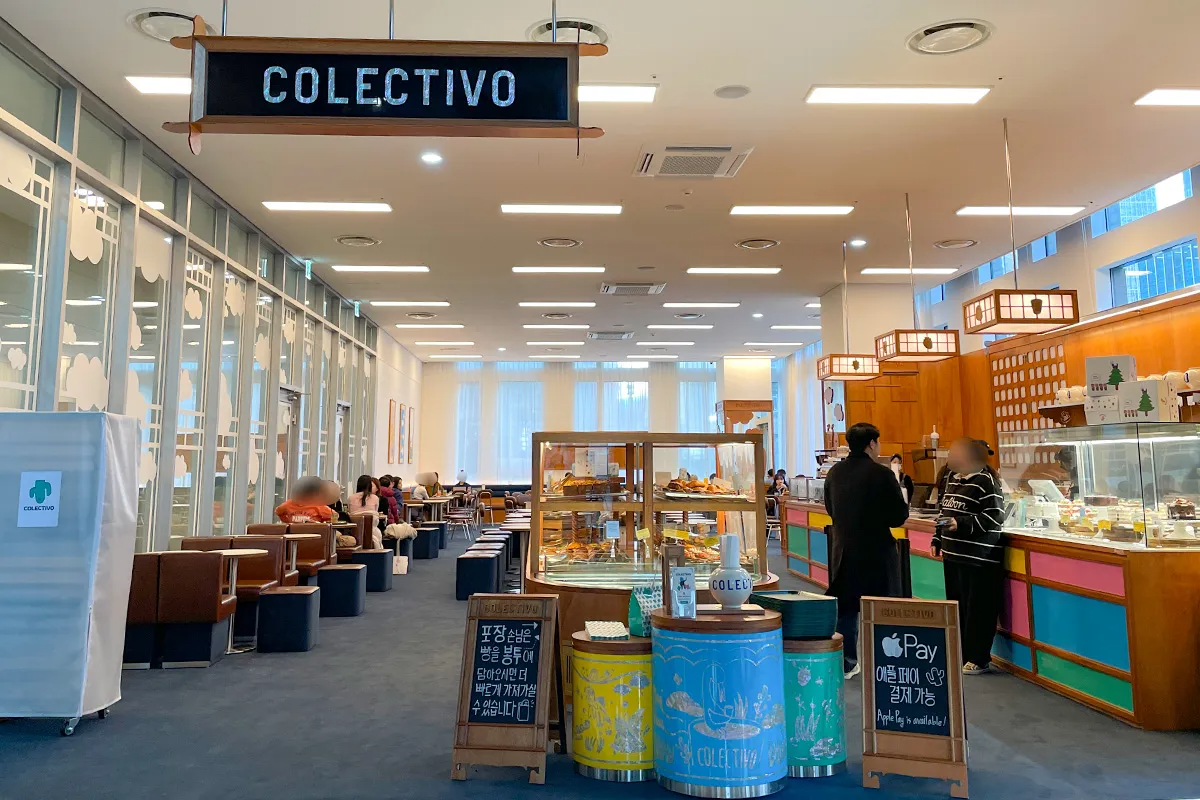 Entrance of COLECTIVO Euljiro Pine Avenue Cafe with warm wooden interiors and cozy lounge seating perfect for coffee and pastry lovers.