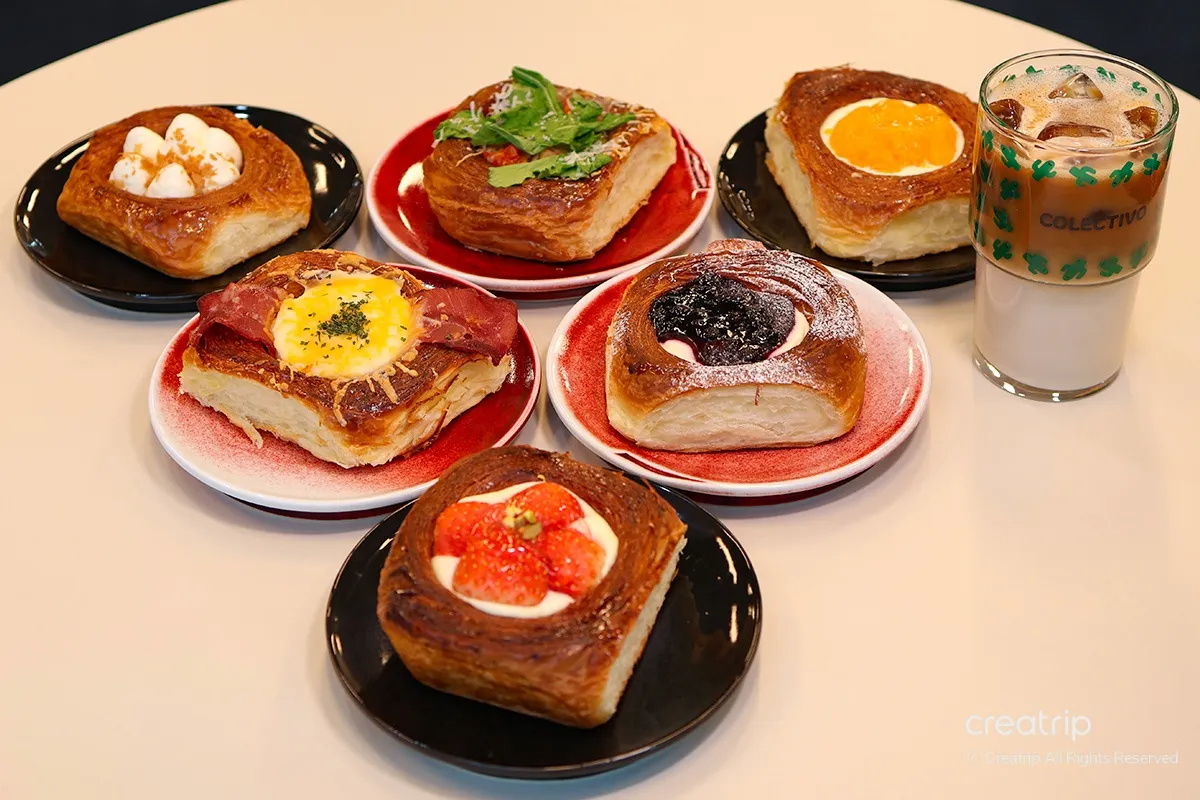 A selection of exquisite pastries and breads at COLECTIVO, beautifully presented on vibrant plates complemented by a creamy oat latte.