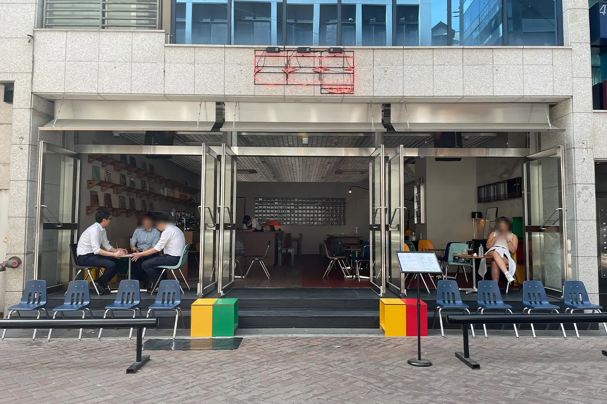 Exterior of Furoa Cafe, Myeongdong showcasing an inviting modern facade with vibrant blue and yellow chairs arranged for outdoor seating.