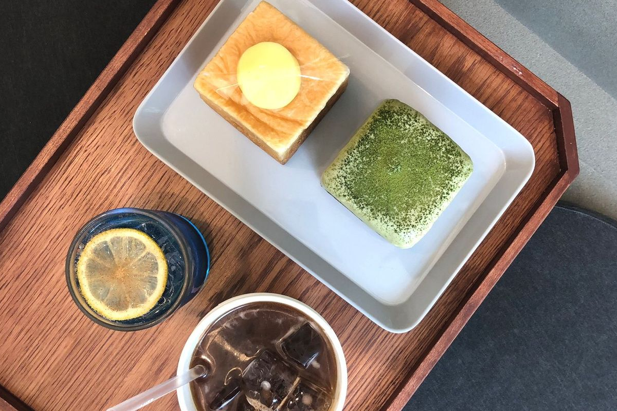 明洞隆珀特咖啡館的經典日式早餐套餐，擺放在木託盤上，搭配檸檬水和黑咖啡，欣賞木質桌面的自然質感。