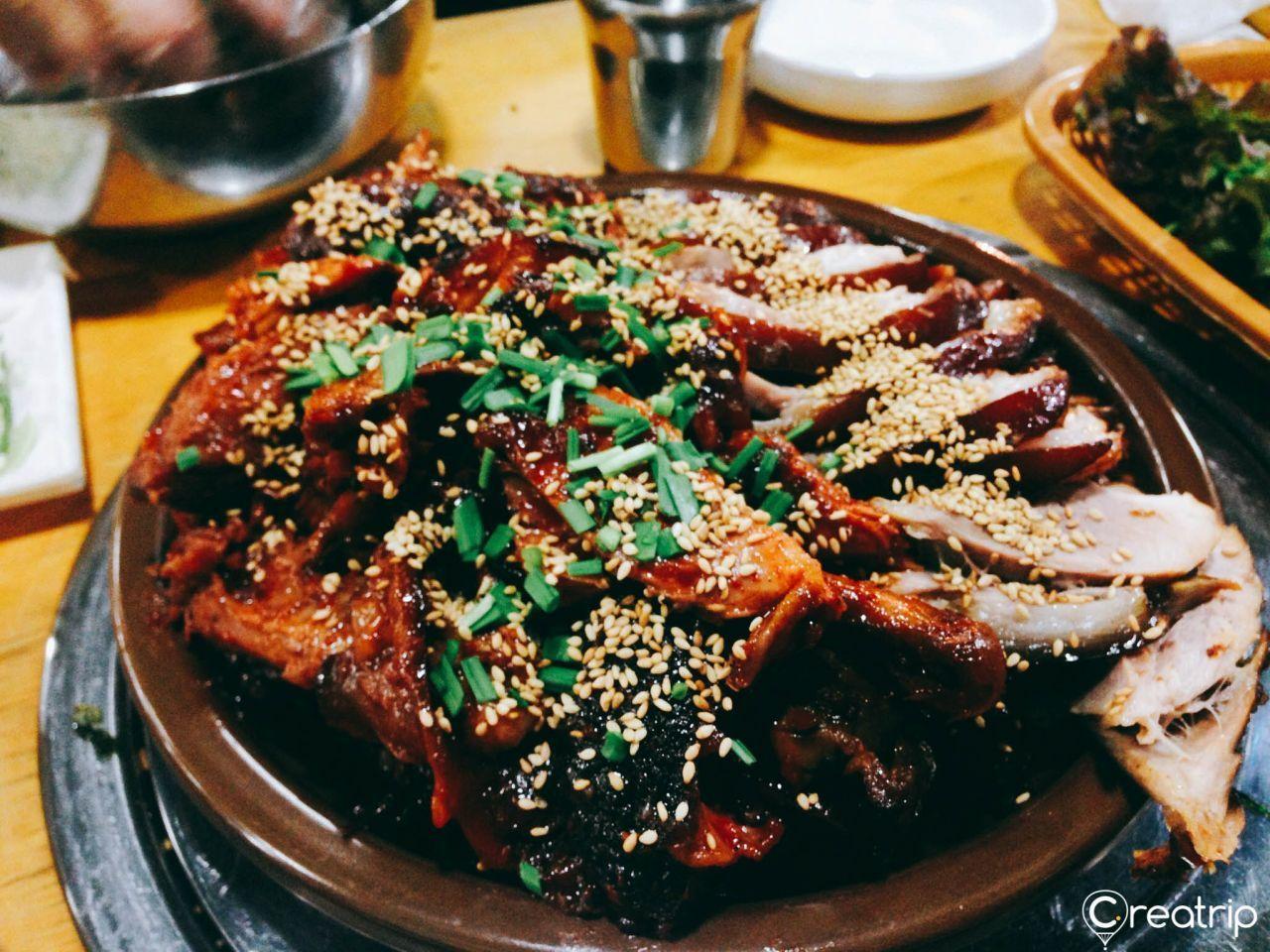 A large platter of succulent marinated Korean pork from Jokbal restaurant, garnished with sesame seeds.